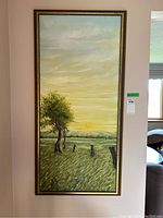 Full view of the vertical oil painting showing a grassy field with trees, wooden fence posts, and a setting sun. Framed in a thin gold frame.