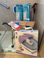 Entire lot overview showing all items in bathroom corner including shower chair, foot bath box, foot massager, cane and accessories.