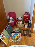 Overview of lot showing vintage kids records, books, basket with stuffed animals, colored pencils and containers, and Disney Cars suitcase.