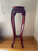 Full view of tall carved wooden plant stand with curved legs.