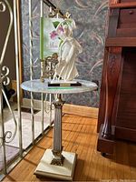Full view of the Italian marble top pedestal table with the white classical statuette and brass easel on top
