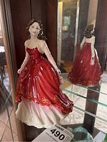 Front view of the Royal Doulton Special Occasion figurine in red gown, displayed inside cabinet with mirror reflecting the back.