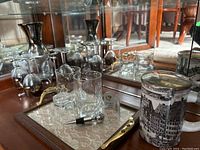 Full view of the wine carafe, tray with wine glasses on stand, highball glasses, porcelain mug with lid, wine stopper, and corkscrew opener.