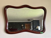Front view of a rectangular wall mirror with a dark wood frame mounted on a wall.