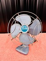 Front view of the vintage metal electric fan with a protective cage and blue central branding marked Torcan.