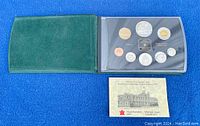 Full set display showing closed green case and protective plastic case holding the coins alongside certificate.