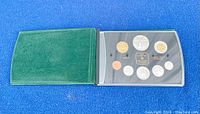 Green cover opens to reveal 8-coin proof set in clear display case.