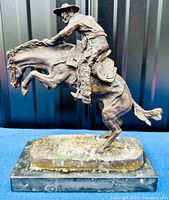 Full side view of bronze figure mounted on marble base