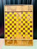 Full view of the antique wooden game board showing yellow and brown checkered pattern with rustic wear and wooden border.