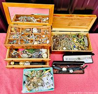 Overview of two wooden jewelry boxes, one turquoise box, and three watch cases filled with jewelry