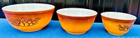 Set of three Pyrex Old Orchard pattern nesting mixing bowls in bright orange with fruit pattern, no chips or cracks