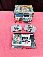 Stack of five original game boxes for NHL '96, F22, Bulls Blazers, and others, viewed from the side to show titles.