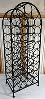 Full front view of freestanding wine rack showing three columns of circular bottle holders and arched top