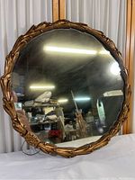 Front view of round mirror showing composite gold-tone ornate frame and hazed mirror surface.