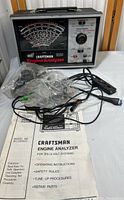 Craftsman engine analyzer device with cables and manual displayed on table.