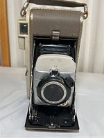 Front view of vintage Polaroid Model 80A camera showing extended bellows and lens assembly with light surface rust and wear.