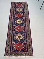 Top down view of Persian runner rug showing alternating red and cream geometric medallions on dark blue field with floral border.