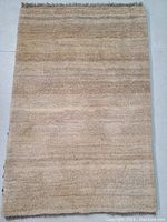 Full view of the beige abrashed Persian Gabbeh wool rug lying flat showing overall color and texture.