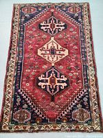 Full view of hand knotted Persian wool rug with tribal medallion design and border.