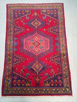 Top view of the hand knotted Persian wool rug showing the full geometric design and vibrant blue, red and pink colors with patterned border.