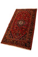 Full view of the red Persian Kashan rug showing intricate floral medallion design and navy border with floral motifs.