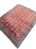 Full view of the rectangular Persian Turkmen wool rug showing intricate geometric pattern with star and square shapes in red, blue, and yellow.