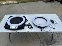 Both Neewer ring lights laid out on a white table, alongside power adapters and a carrying bag.