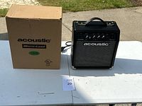 Amplifier next to the original box on a white table outside.