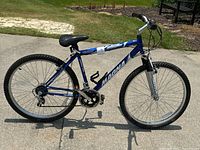 Side view of blue Magna boys mountain bike showing frame, wheels, pedals, and saddle.