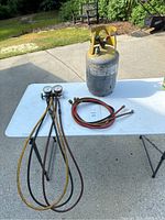 Full view of the refrigerant tank, manifold gauge set with three hoses including black, yellow, and red.