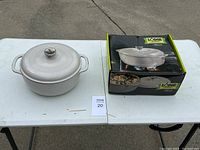 Photo of the Lodge enamel Dutch oven next to its box, showing oyster white color and size.