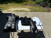 Black and white mannequin torsos laid out on tables and ground. Visible hooks, holes and muscular details on adult torsos.