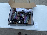 Photo of the pair of roller skates in their box showing multi-color leopard print pattern and black wheels.
