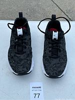 Overhead image of the pair of Nike shoes showing patterned black upper, black laces, red inner lining, and white sole.