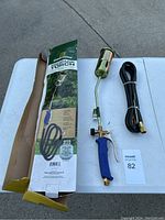 Photo showing propane torch, hose, manual igniter, and original box laid out on table.