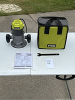 Full view of Ryobi router with carrying case, wrench, and instruction manual on table