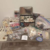 Wide view of large collection of buttons in bags, cards and containers with metal tin and cards of gold and cream buttons