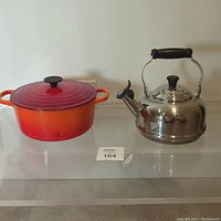 Full lot view showing Le Creuset cast iron Dutch oven and stainless steel whistling tea kettle