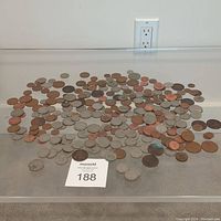 Coins spread on a table showing a mix of copper and silver-colored coins with various sizes and conditions.