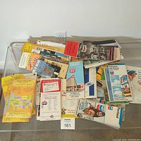 Photo showing assortment of folded vintage maps and brochures in a pile highlighting Metsker County Maps and other regional maps.