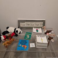 Photo showing Snoopy book, Pooh book, stacks of Mr Men and Little Miss books, and four Beanie Babies plush toys with Bristow cartoon strip in background.