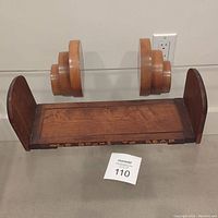 Extendable wooden bookshelf with carved woman on each side and 'Old Books To Read' text on front, positioned on floor against wall.
