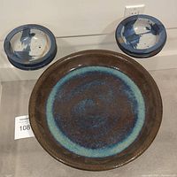 Overall view of the large serving dish and six smaller bowls arranged on floor against wall.