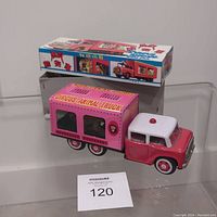 Toy and original box displayed side by side on a glass shelf.