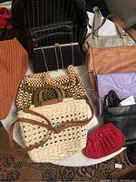 Wide shot of various women bags and purses arranged on a marble or stone table surface showing leather, beaded, knit and woven styles.
