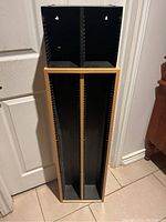 Two CD storage racks stacked vertically showing wood frame and black interior with slots for CDs.