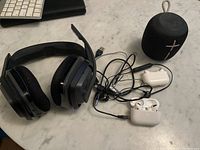 Overview photo showing the ION Audio headphones, UE Wonderboom speaker, wired earphones, Apple AirPods, and charging cases placed on a marble surface.