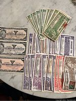 Photo shows assortment of Canadian Tire paper money notes fanned out on a gray surface, displaying denominations and vintage designs.