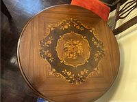 Top view showing round wood tabletop with central inlaid floral marquetry medallion and decorative border