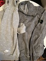 Nike gray hoodie with white swoosh pattern and logo on front pocket, shown laid flat with hood visible